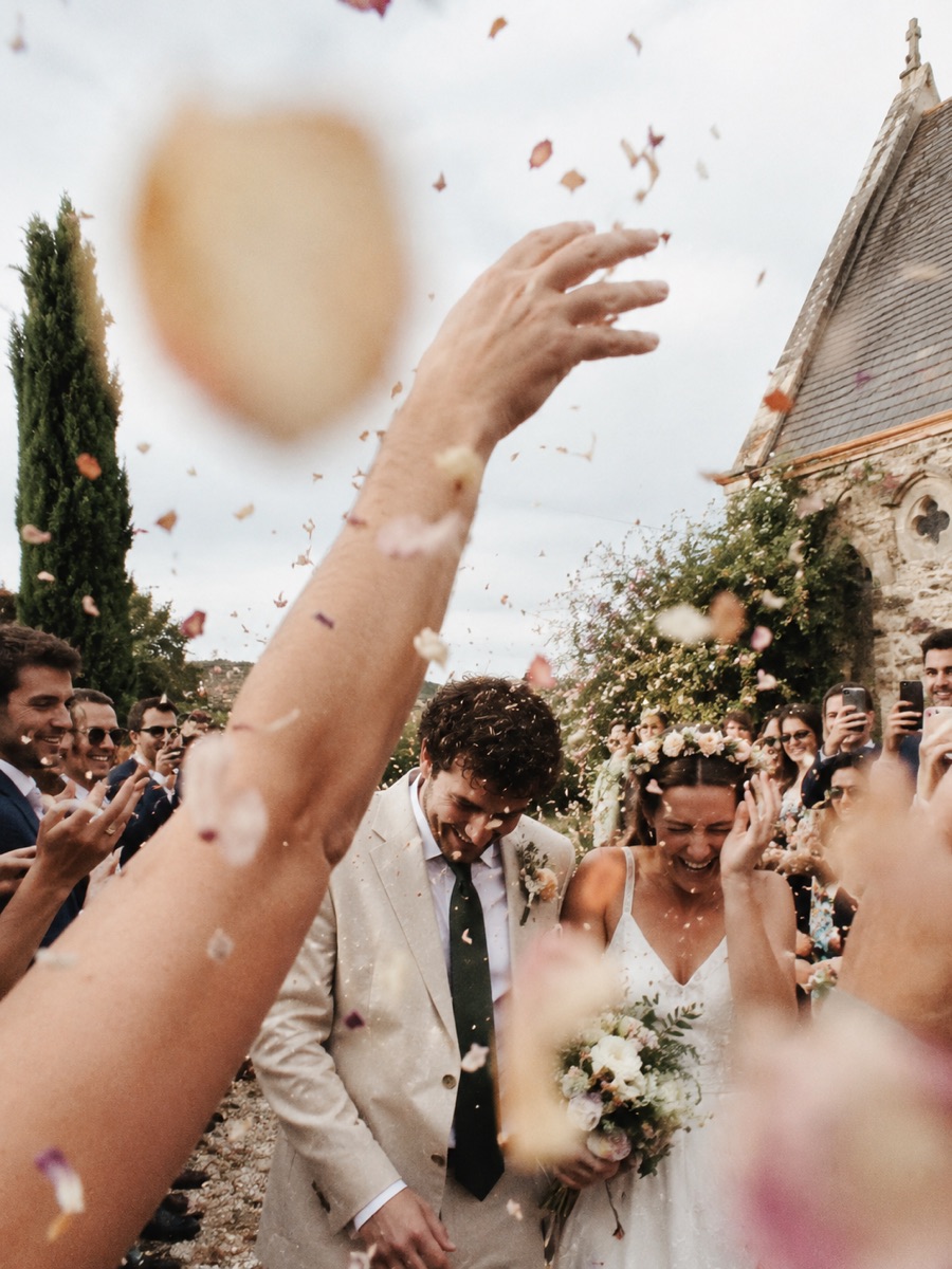 The couple walking through confetti, seen from inside the line throwing it