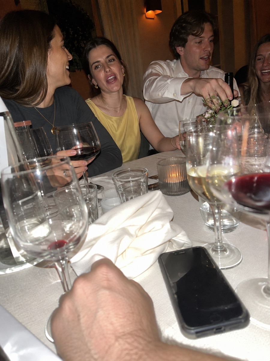 Guests laughing across a reception table, seen from a seat at it
