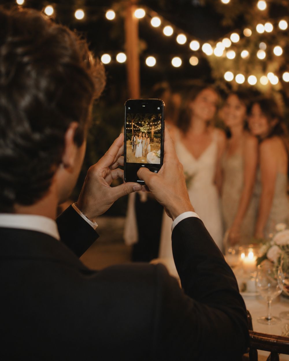 A wedding guest taking a photo on their phone, the shot visible on screen